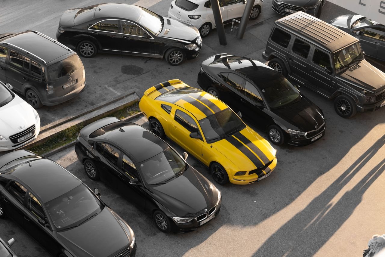 why-choose-us Top view of various cars parked in a parking lot, featuring a yellow sports car.